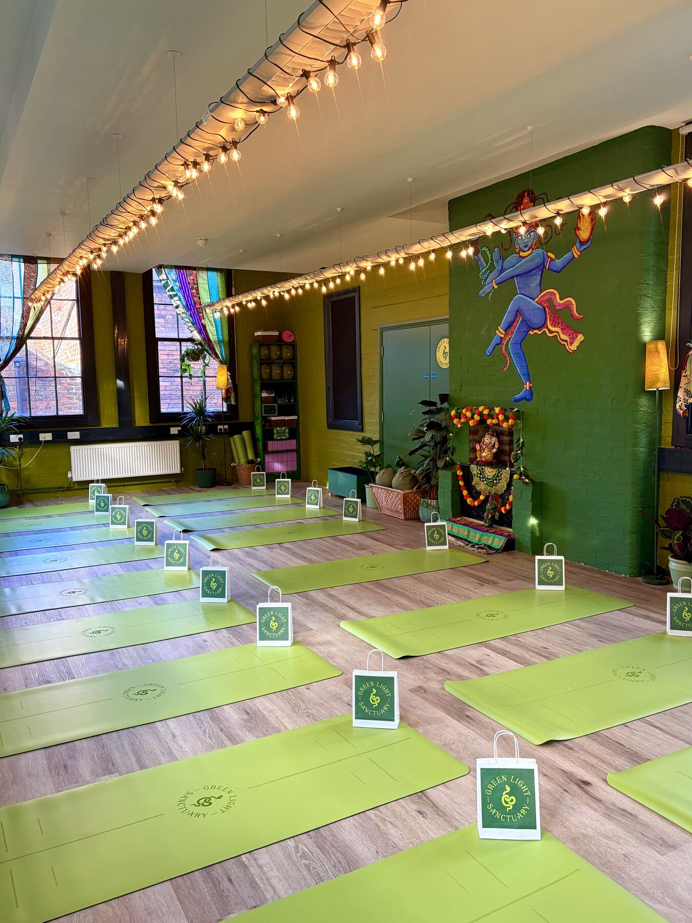 Mural of a dancing deity painted on the studio wall, mats laid out ready for class