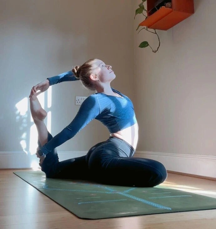 Ella in a seated backbend pose holding her foot